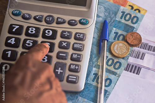 Real - Brazilian currency. Real notes on a wooden table with a calculator and pen in the composition. Concept of economy, finance, Selic rate, taxes and financial planning