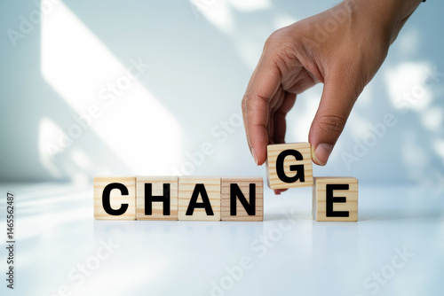Close-up of hand changing wooden blocks to spell 'CHANGE'.