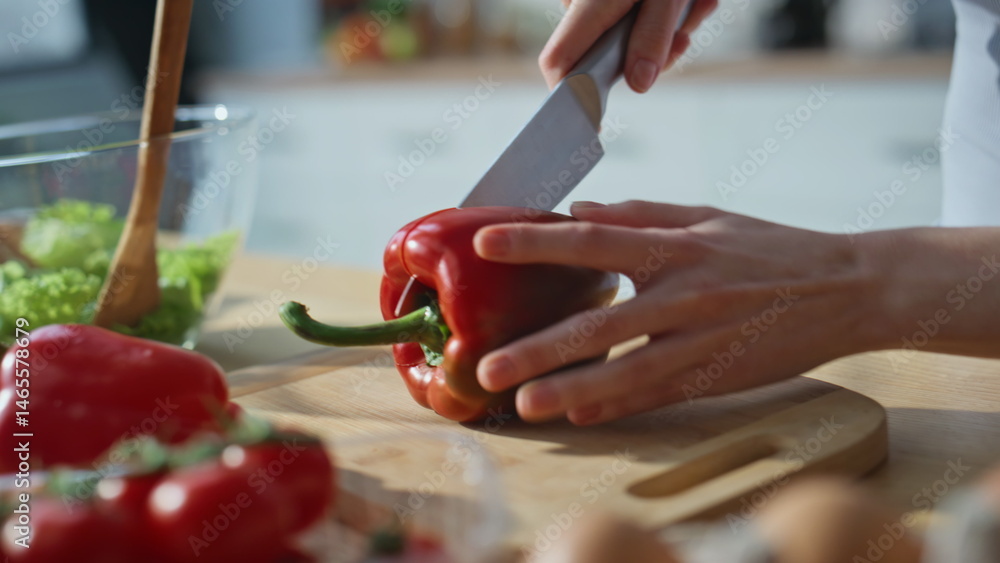Hands chopping red bell pepper on kitchen countertop closeup. Woman preparing