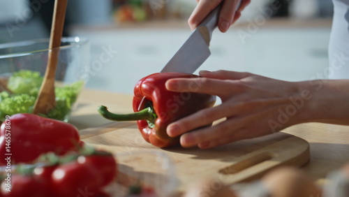 Hands chopping red bell pepper on kitchen countertop closeup. Woman preparing