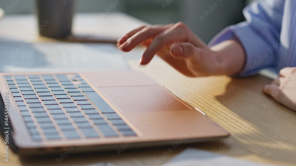 Girl hand tapping laptop touchpad browsing website at apartment table closeup.