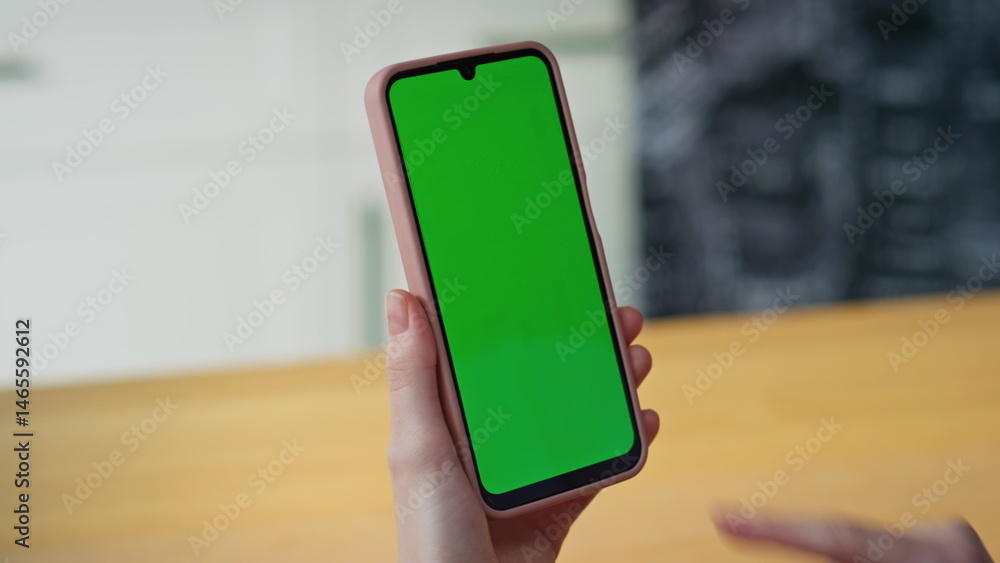 Unknown girl tapping greenscreen cellphone reading message at home closeup.