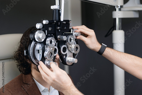 Obraz na płótnie Male patient undergoing eye exam with optometrist using phoropter in clinic w salonie