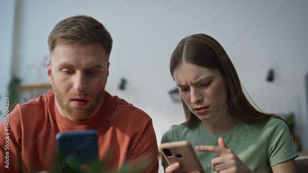 Spouses worried smartphone message sitting living room closeup. Serious family