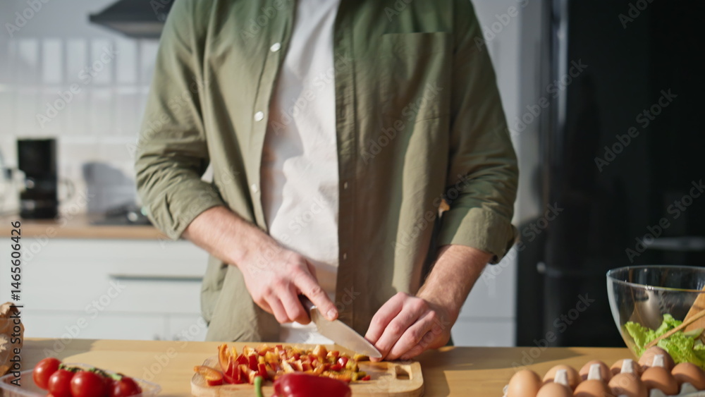 Guy hands slicing ingredients at kitchen listening music in headphones closeup.