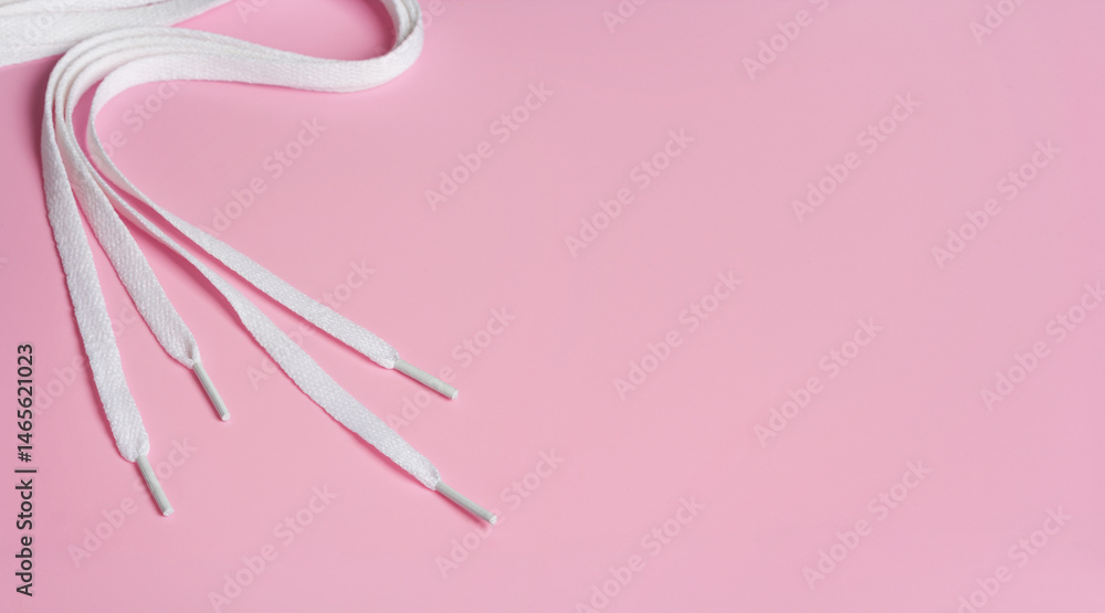White shoelaces on light pink background with copy space
