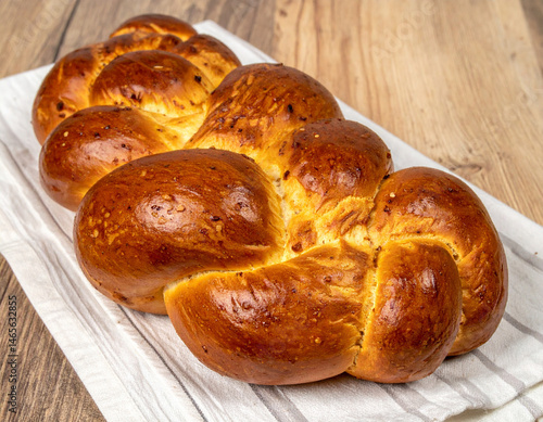 Freshly baked challah bread, braided and golden brown, representing a staple of Jewish cuisine and Sabbath tradition. photo