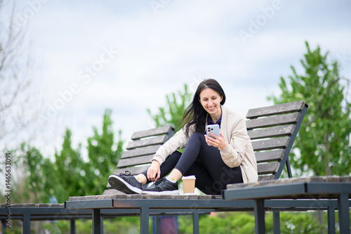 Woman making video call outdoors on lounge chair in park