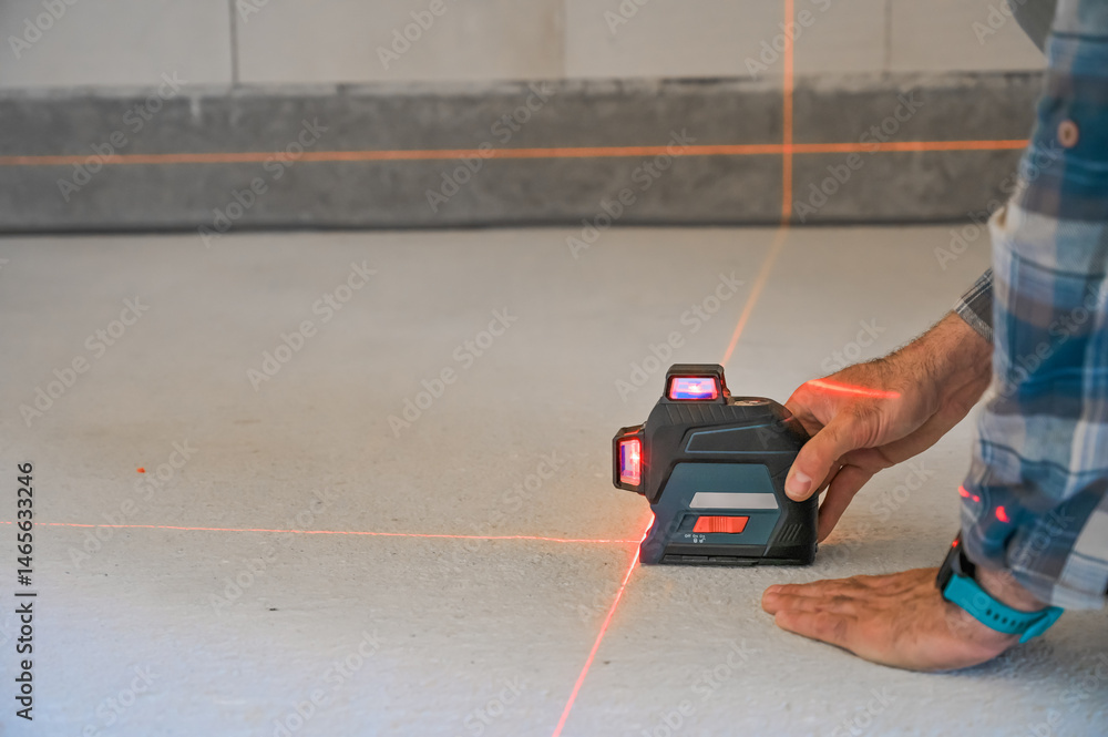 A person using a laser level tool on a smooth surface to ensure accurate measurements, showcasing the practicality of technology in construction and home improvement projects