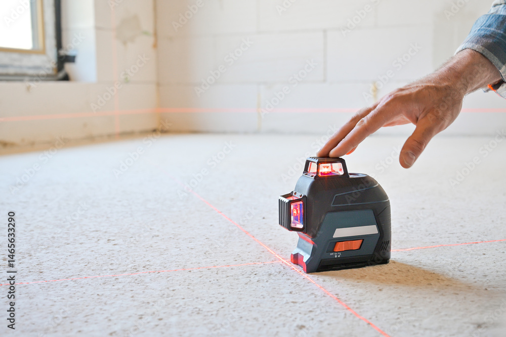 A person using a laser level tool on a smooth surface to ensure accurate measurements, showcasing the practicality of technology in construction and home improvement projects