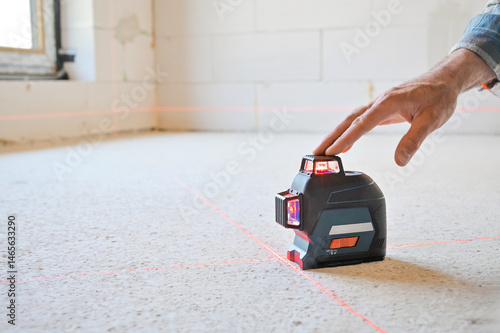 A person using a laser level tool on a smooth surface to ensure accurate measurements, showcasing the practicality of technology in construction and home improvement projects