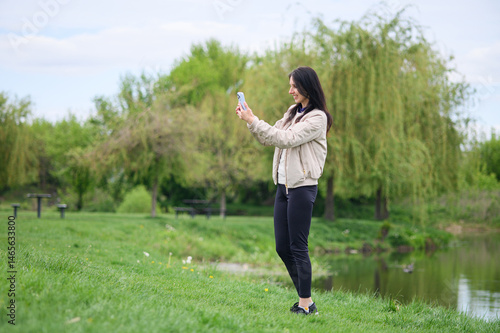 Smiling woman making a video call in park and pointing upward