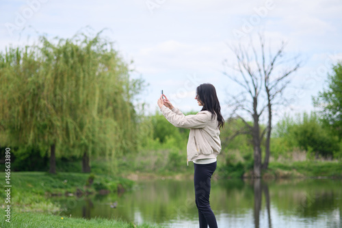 Smiling woman making a video call in park and pointing upward