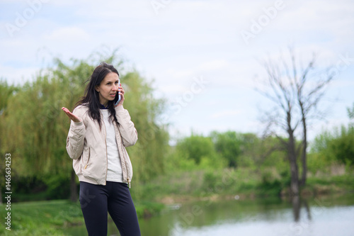 Smiling woman making a video call in park and pointing upward
