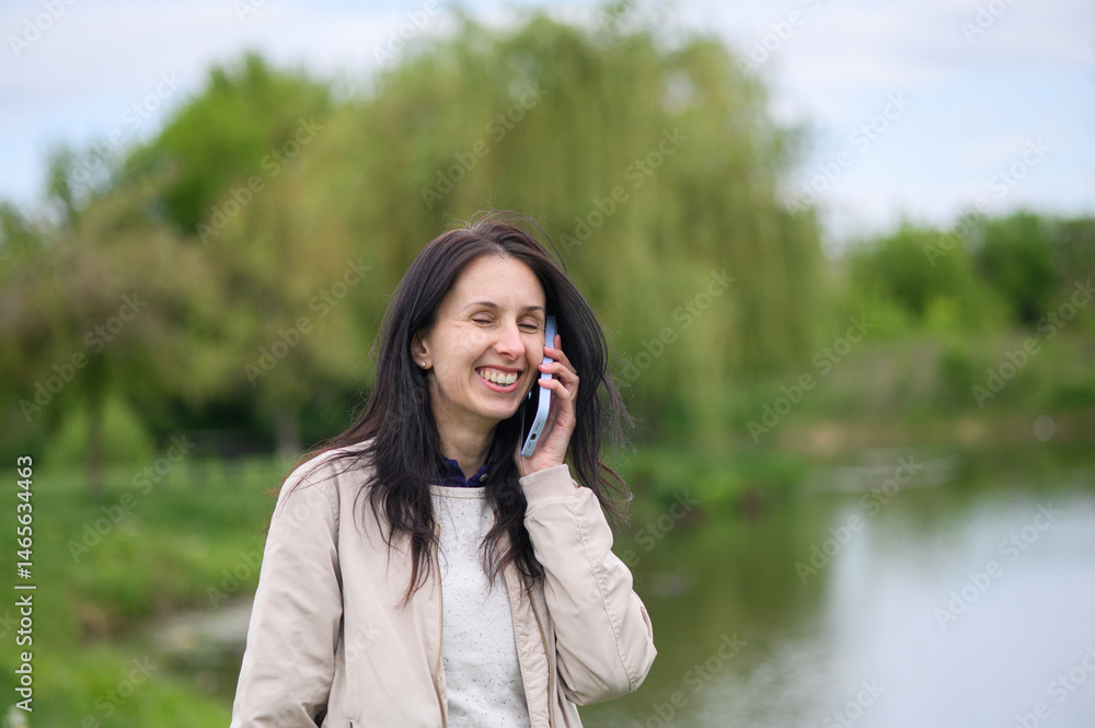 Smiling woman making a video call in park and pointing upward Smiling woman making a video call in park and pointing upward