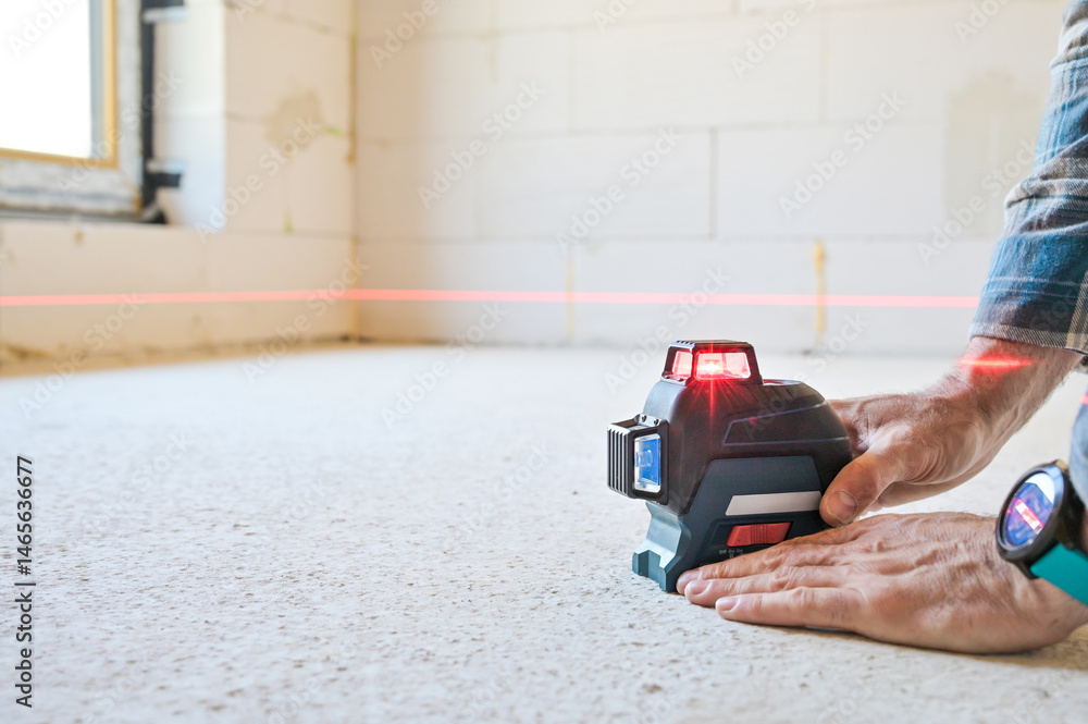 A person using a laser level tool on a smooth surface to ensure accurate measurements, showcasing the practicality of technology in construction and home improvement projects