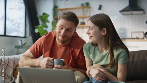 Obraz na płótnie Spouses enjoy online meeting with family using laptop internet at home closeup w salonie