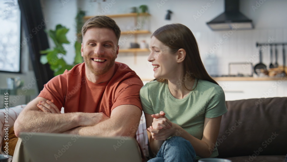 Spouses talking online meeting by laptop at home couch closeup. Smiling couple