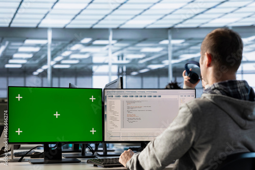 IT expert in server farm using green screen PC ensuring valuable data remains shielded from threats. Man safeguarding hardware against unauthorized access using mockup computer