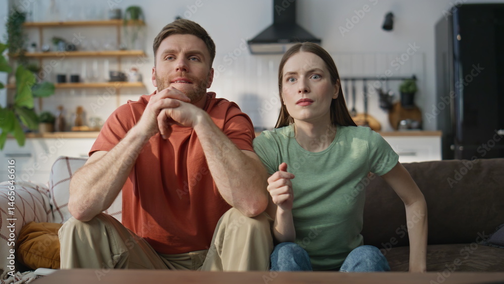 Family pair watching sport championship on TV at sofa closeup. Emotional spouses