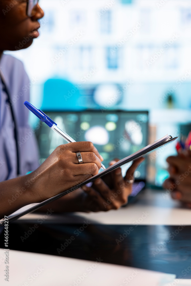 African american nurse takes notes during consultation with old people, creating the healthcare records with symptoms and other problems. Ensuring an easy recovery plan, clinical setting. Close up.