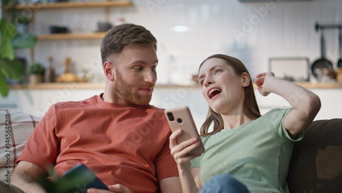 Obraz na płótnie Talking couple holding smartphones sitting cozy couch living room closeup. w salonie