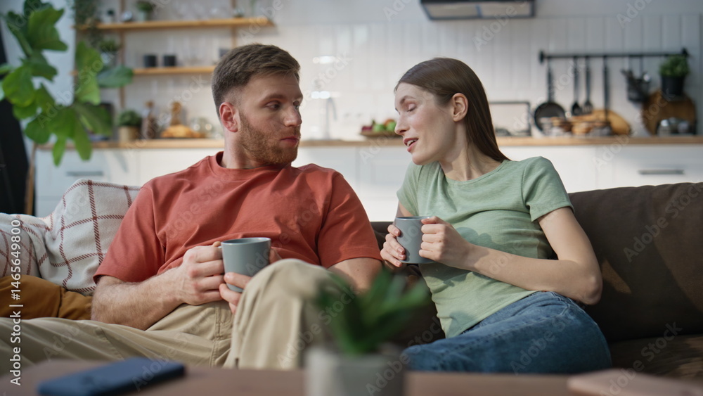Loving husband talking wife drinking coffee together at home couch closeup.