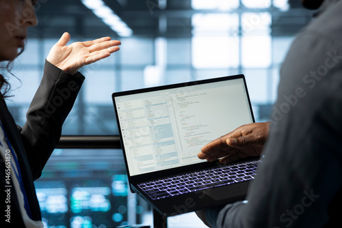 Software developers using laptop in data center, managing server virtualization. IT expert coding on notebook in server room, finetuning network protocols, enforcing advanced security measures