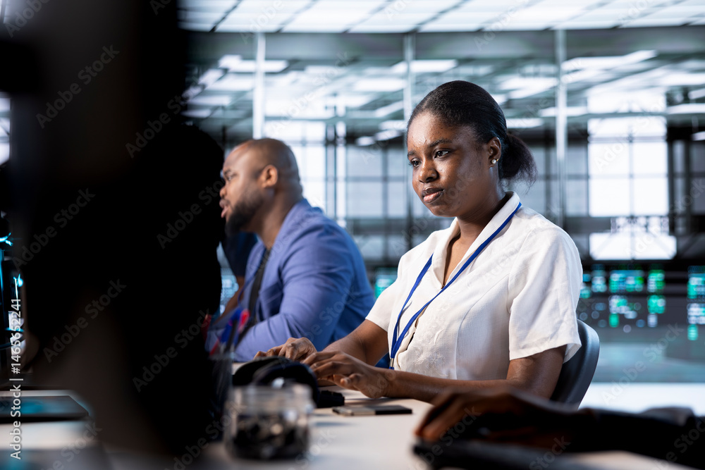 African american admin next to colleagues doing yearly checkup to prolong data center electronics life span and avoid downtime. Woman in server hub monitoring server infrastructure components