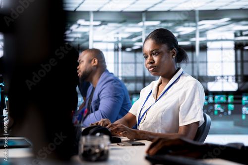 African american admin next to colleagues doing yearly checkup to prolong data center electronics life span and avoid downtime. Woman in server hub monitoring server infrastructure components