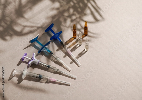  syringes, ampoules, top view, medical gloves, disposable cap arranged on a light background, natural sunlight. medical preparation or cosmetic procedure setup