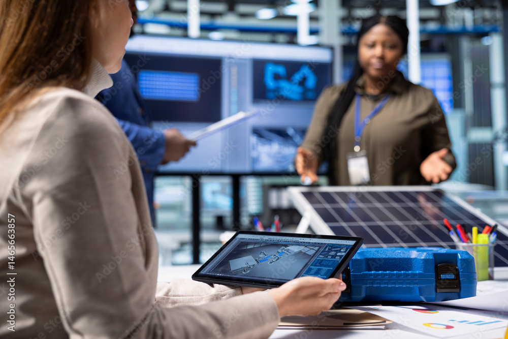 Photovoltaics factory researching team monitoring system performance using tablet. Solar panels plant management executives tracking energy production using device software