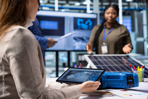 Obraz na płótnie Photovoltaics factory researching team monitoring system performance using tablet. Solar panels plant management executives tracking energy production using device software w salonie