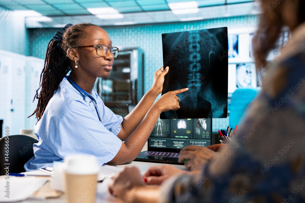 African american assistant sharing medical records information with old patient in office, reviewing x ray diagnostics and MRI scans to focus on accurate treatment and recovery. Lab test feedback.