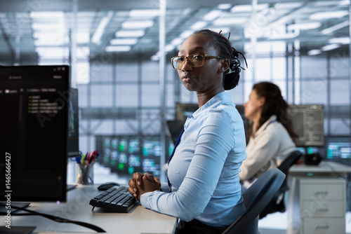 African american engineer managing and optimizing data center infrastructure for maximum efficiency and uptime. Woman in server room maintaining optimal system performance, performing backups