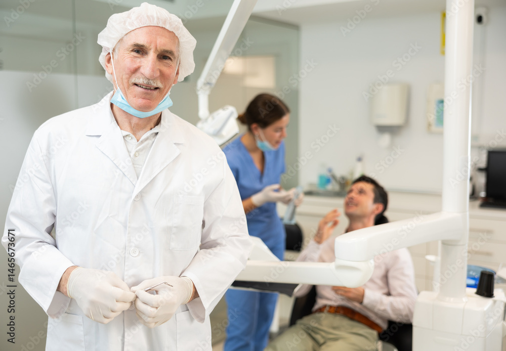 Obraz premium Mature man dentist posing while examining patient in dental clinic