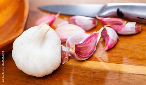 Whole garlic with separated cloves lying on a wooden table. Close-up image..