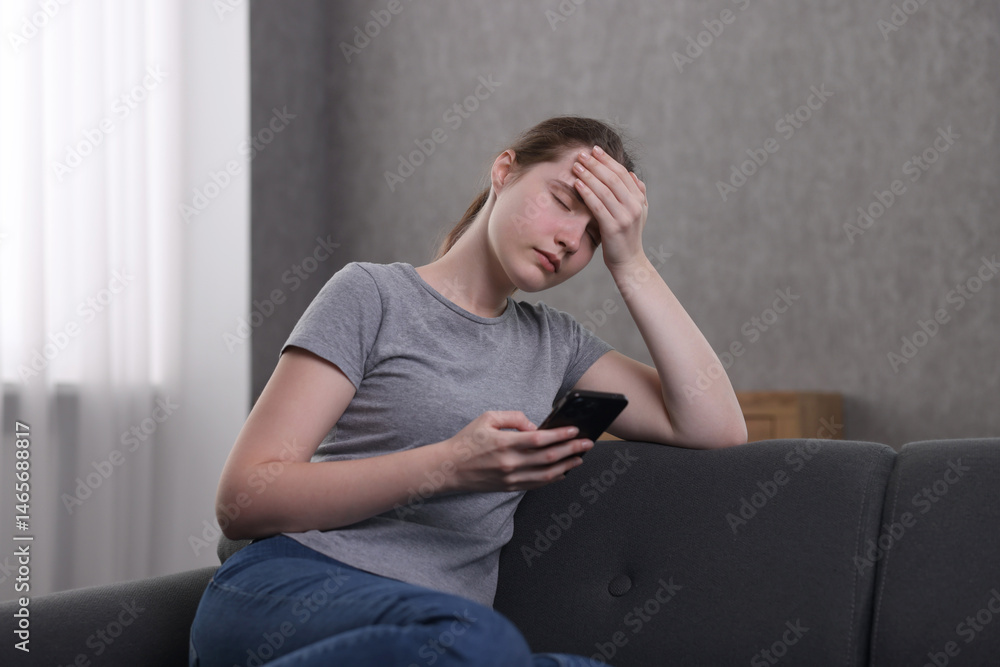 Fototapeta premium Depressed woman calling hotline for mental health help on sofa at home