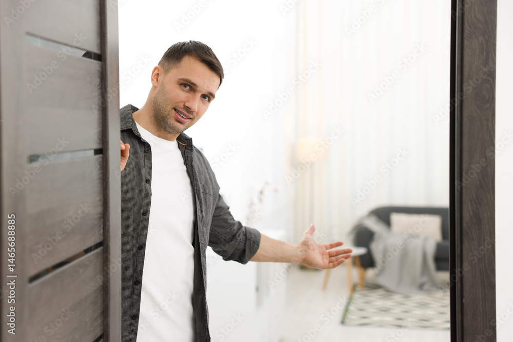 Cheerful man welcoming guests to his apartment. Space for text Cheerful man welcoming guests to his apartment. Space for text