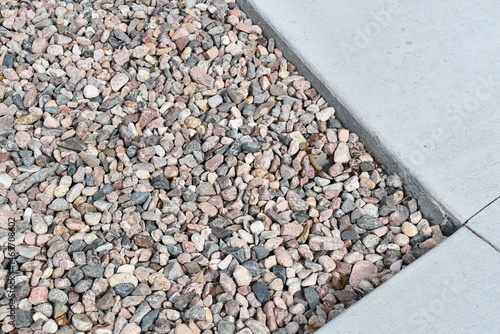 Pea gravel around sidewalk. Corner of sidewalk.