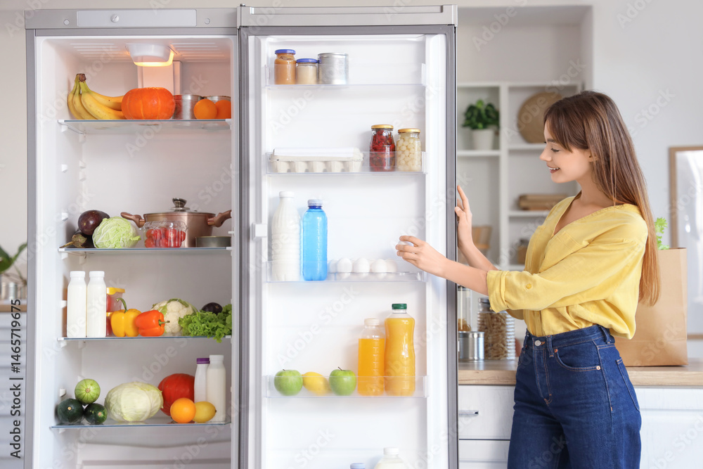 Young woman taking egg from open fridge in kitchen Young woman taking egg from open fridge in kitchen