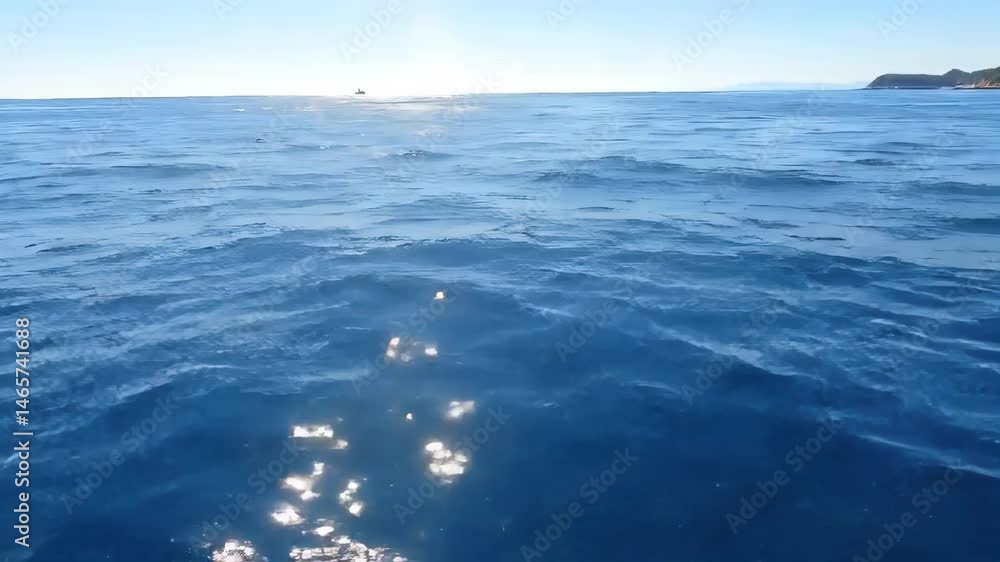 Vibrant Blue Sea with Sparkling Surface Reflecting Sunlight on a Clear Day at the Coastline with Distant Horizon Featuring Rocky Land Mass Vibrant Blue Sea with Sparkling Surface Reflecting Sunlight on a Clear Day at the Coastline with Distant Horizon Featuring Rocky Land Mass