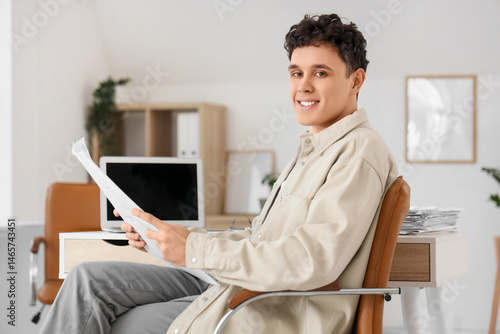 Young man reading newspaper...