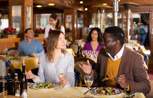 Wallpaper Mural Smiling european woman with cheerful african american friend meeting over dinner with wine in restaurant.. Torontodigital.ca