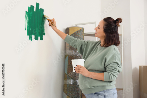 Young pregnant woman painti...