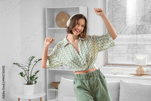 Beautiful young woman in headphones dancing at home