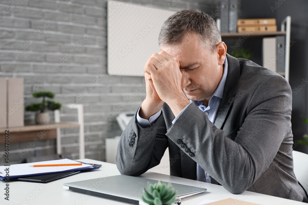Mature businessman feeling unwell at table in office Mature businessman feeling unwell at table in office