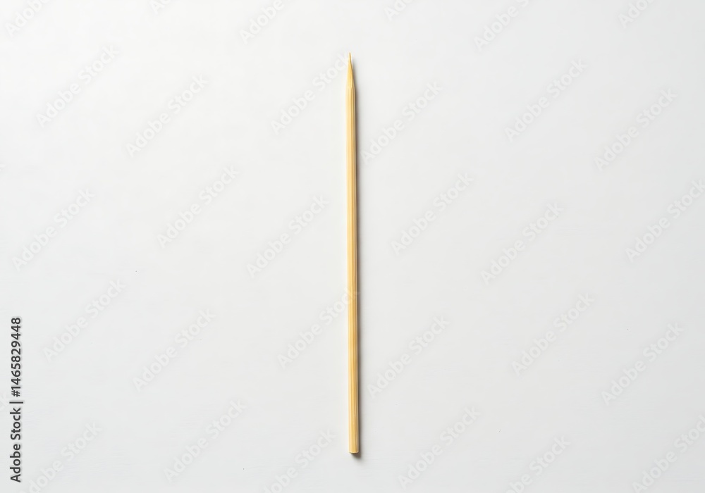 A single wooden skewer centered on a white background in a studio shot with soft lighting