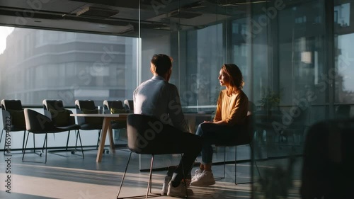 Two Young Professionals Engaged in Meaningful Conversation in Modern Office with Natural Light