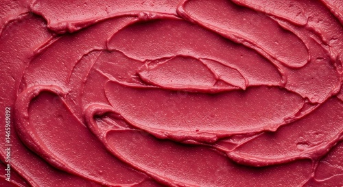 Close-up of vibrant red frosting swirled atop ice cream, evoking a summer treat with rich texture and color